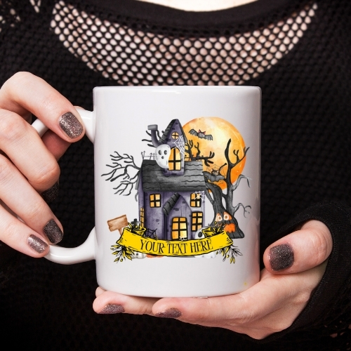 Ceramic Halloween mug depicting a cartoon spooky house with ghosts in the windows, bats flying around, and a large full moon, perfect for festive drinks.